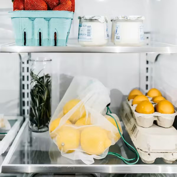 reusable product bags and glass food containers in refrigerator