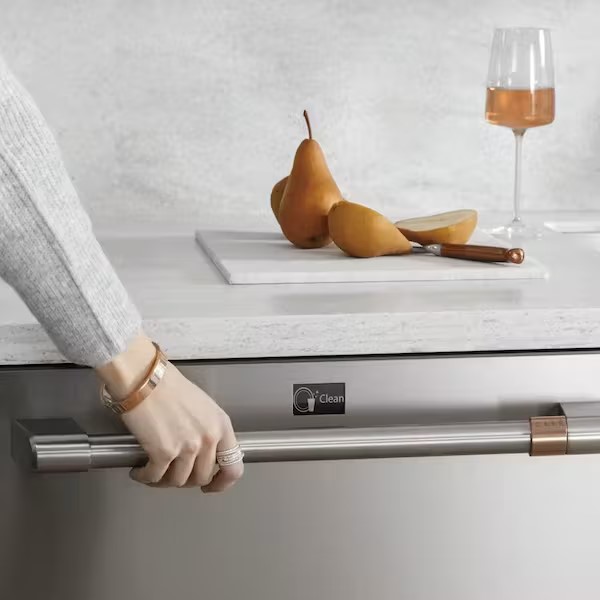 hand on dishwasher handle with pears and glass of wine above